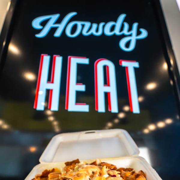 Howdy Hot Chicken sign with a takeout container of fried chicken and sauce below.