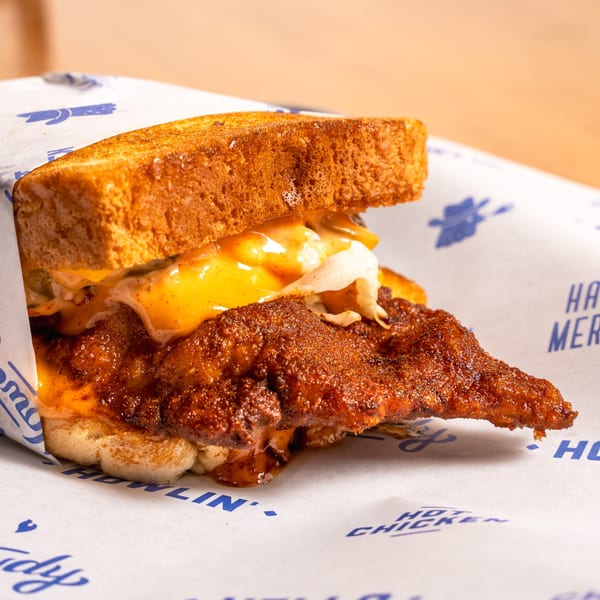 Howdy Hot Chicken sandwich with crispy fried chicken, melted cheese, and slaw on toasted bread.