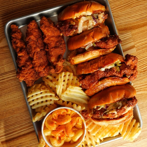 Howdy Hot Chicken platter with fried chicken tenders, sliders, waffle fries, and mac and cheese.